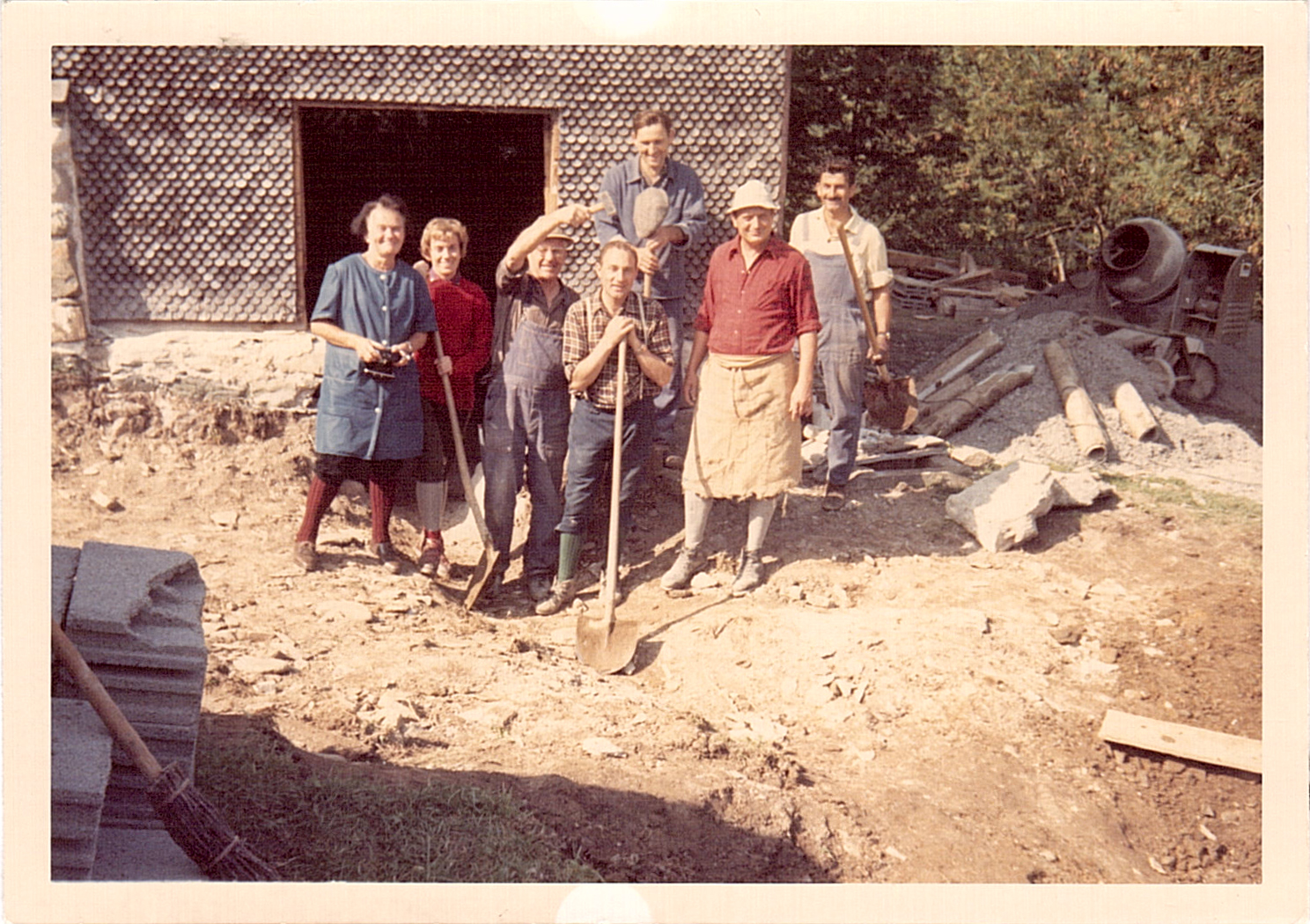 Gruppe mit Schaufeln in Arbeitskleidung vor der Hütte