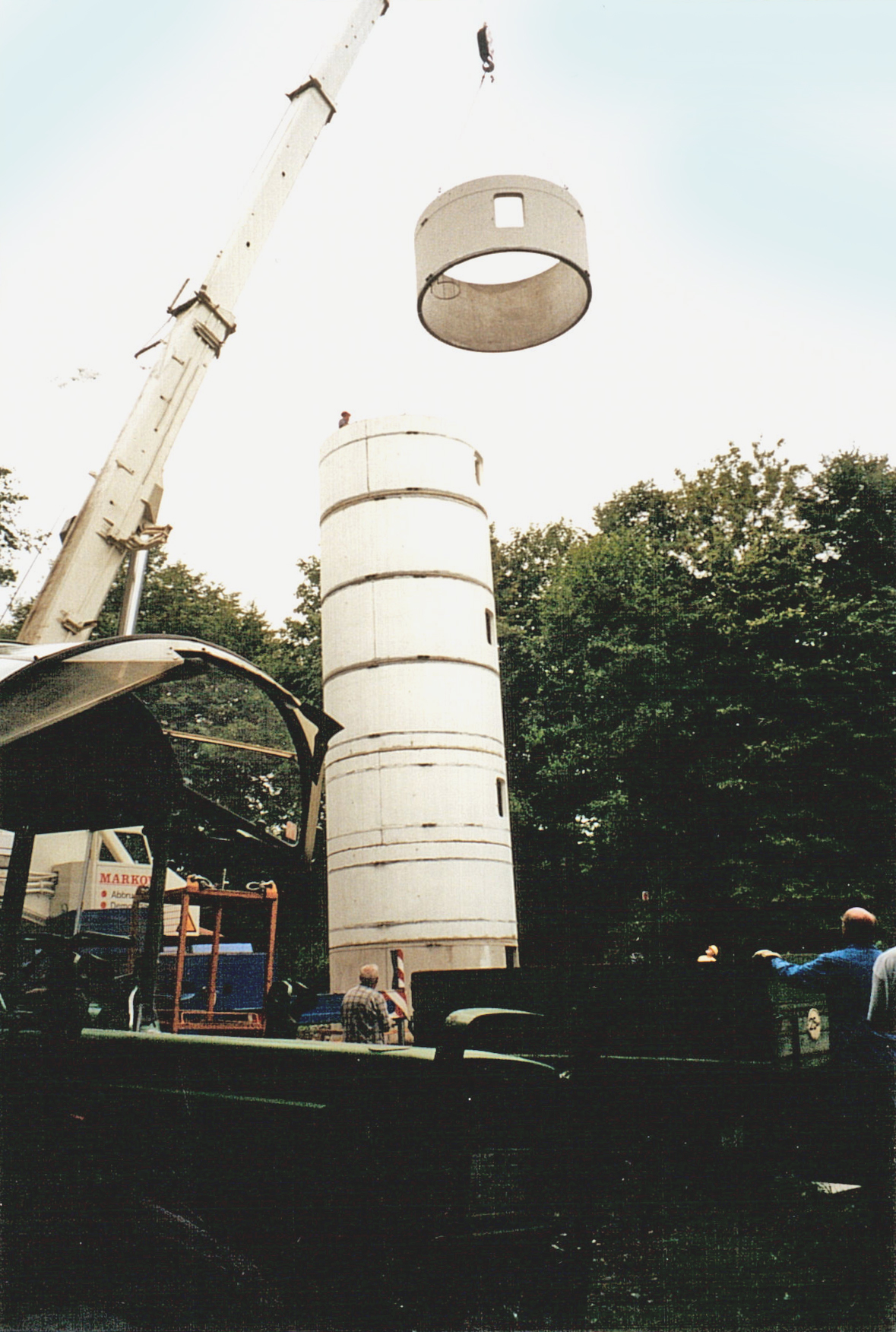 ein Betonring wird gerade mit Kran auf den Turm gesetzt